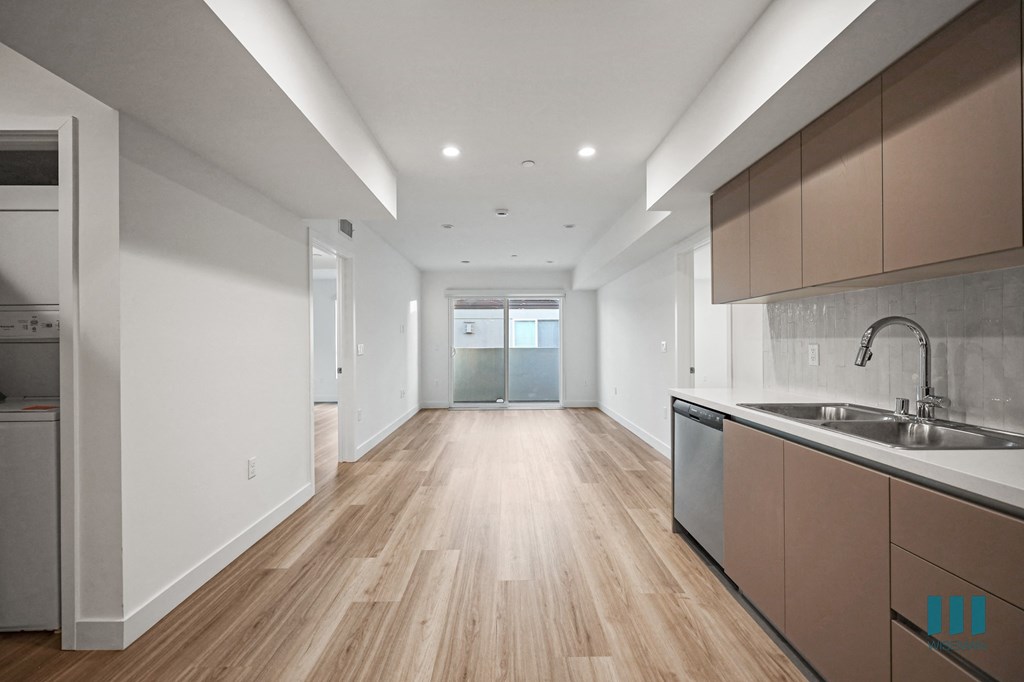 A modern kitchen with wooden floors and white walls.