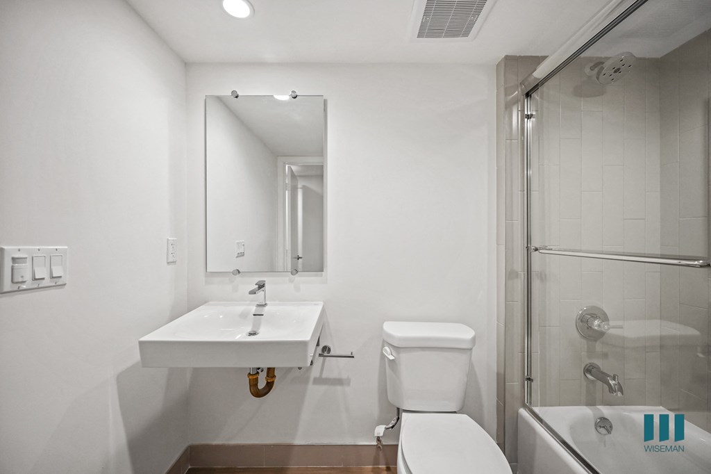 A white bathroom with a sink, toilet, and shower.