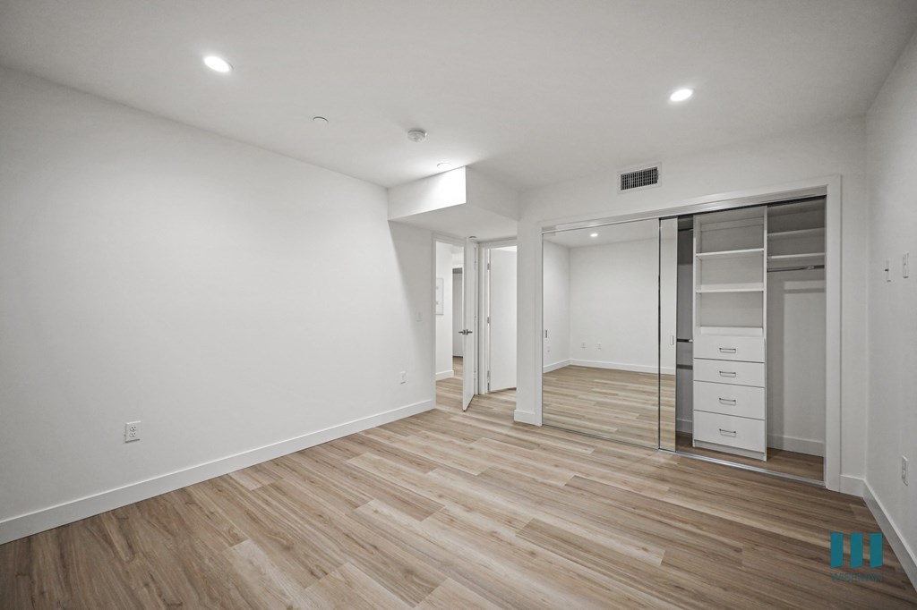 A spacious room with wooden flooring and white walls.