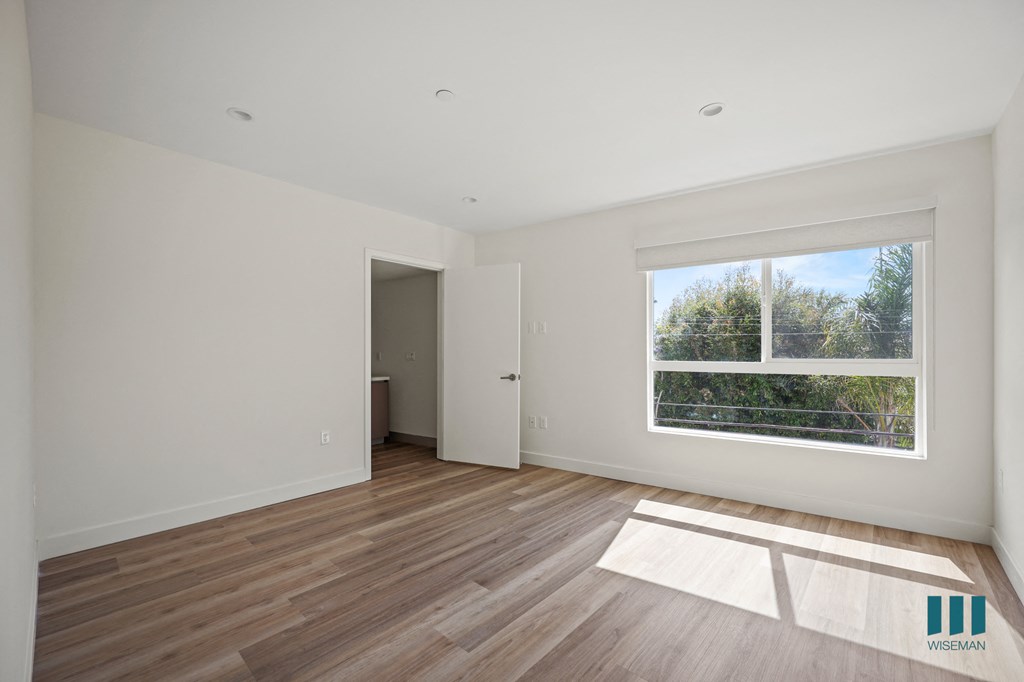 a living room with white walls and wooden floors and a window