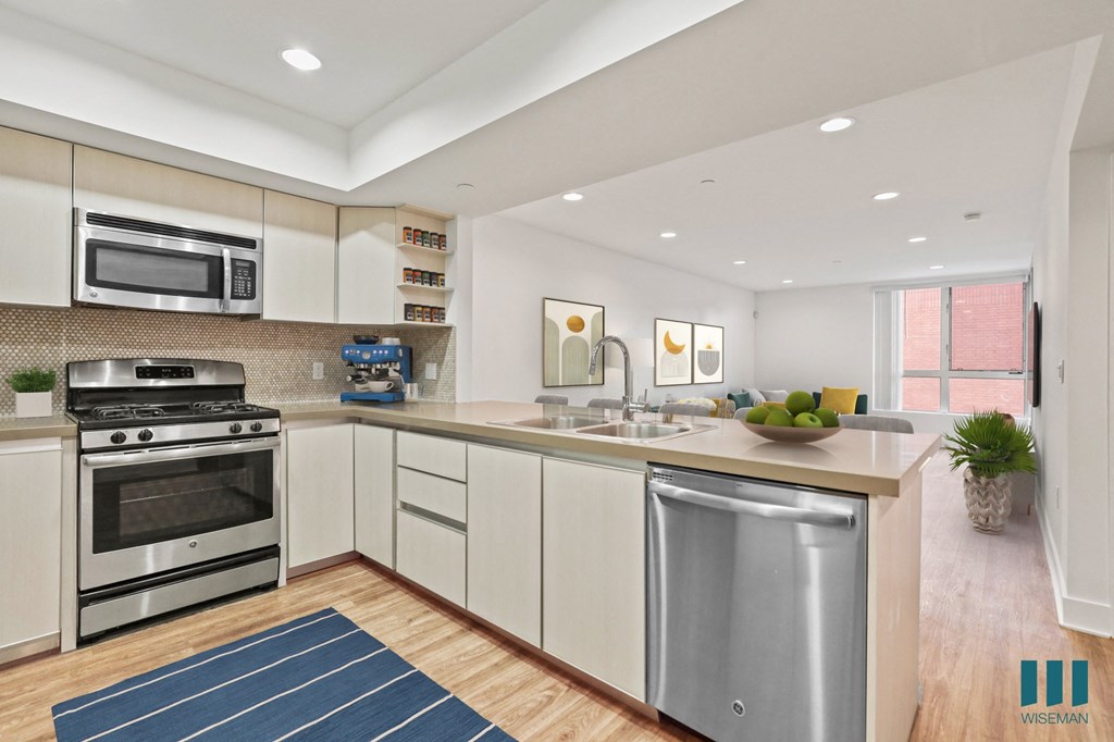 Open-concept kitchen, with Stainless-Steel Refrigerator, Stove, Microwave Oven, Dishwasher, and Countertop Bar