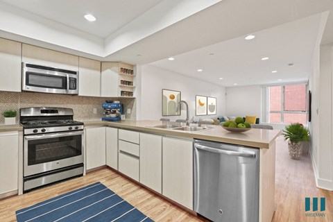 Open-concept kitchen, with Stainless-Steel Refrigerator, Stove, Microwave Oven, Dishwasher, and Countertop Bar