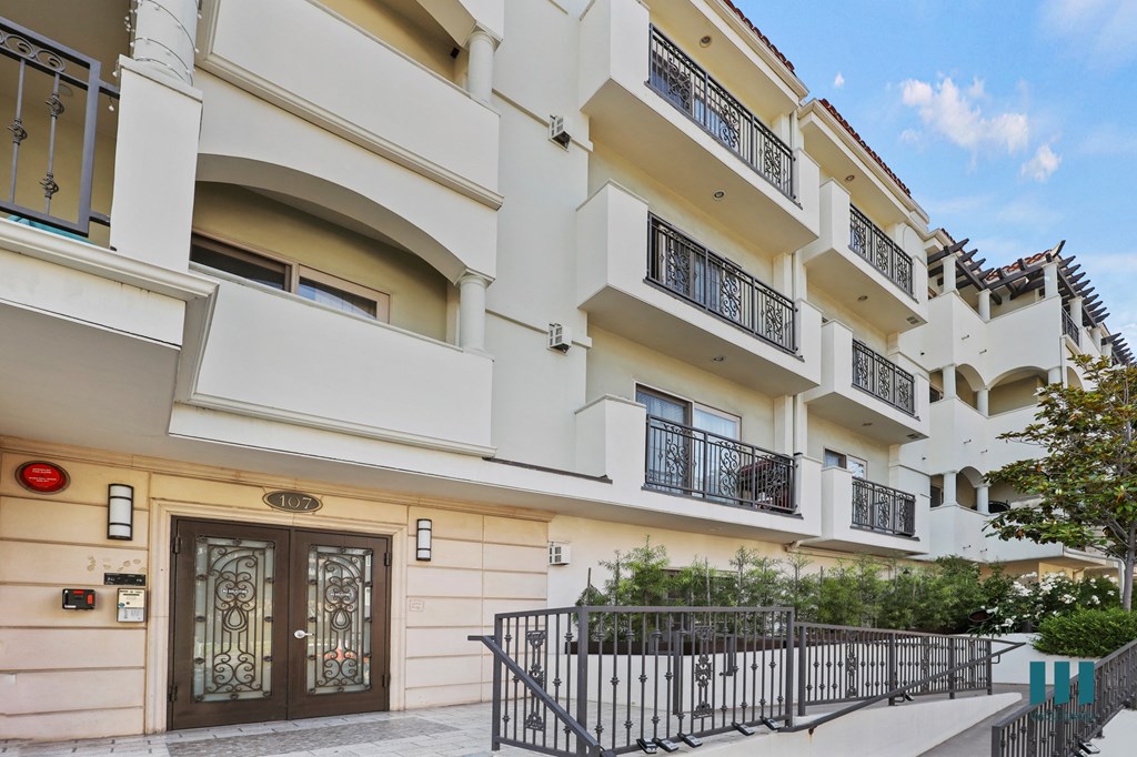 a white apartment building with a staircase and a gate