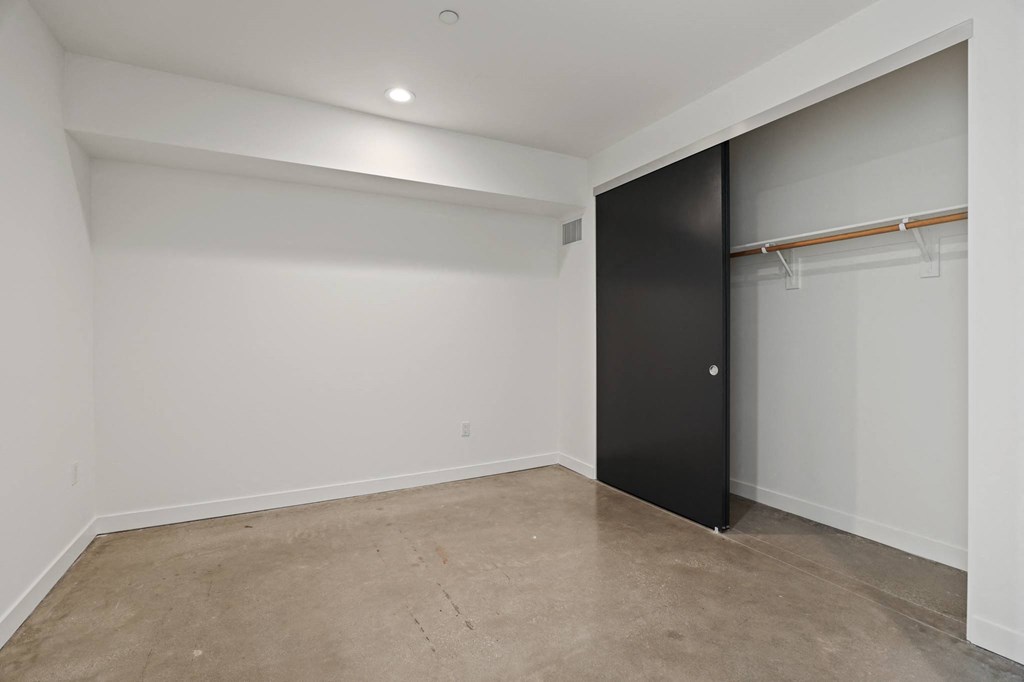 Bedroom with Closet, Recessed Lighting, and Concrete Flooring