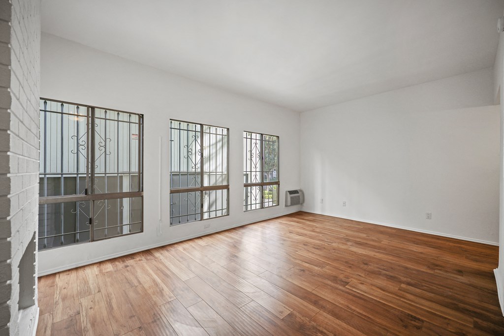 A room with wooden floors and three windows.