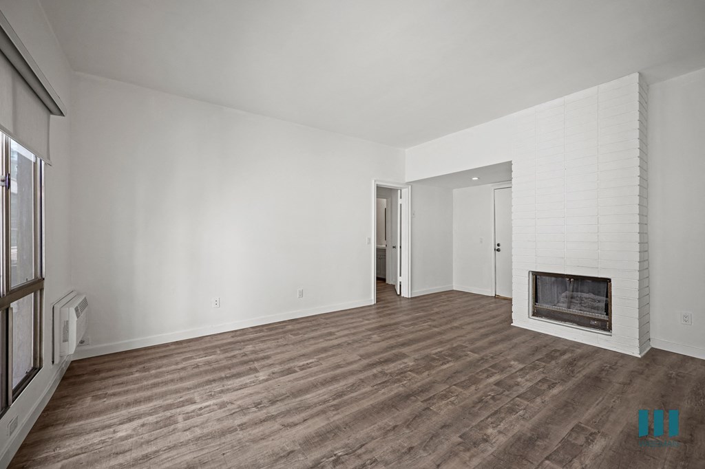 A spacious living room with a fireplace and wood flooring.