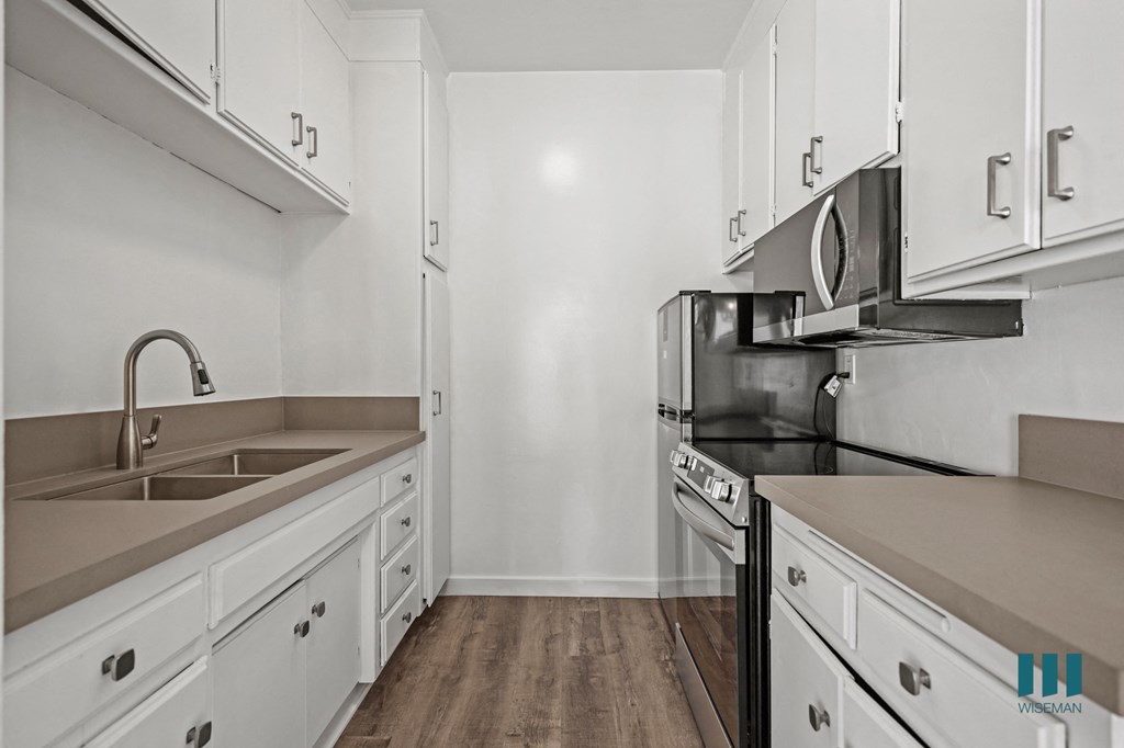 A kitchen with white cabinets and a black stove top oven.