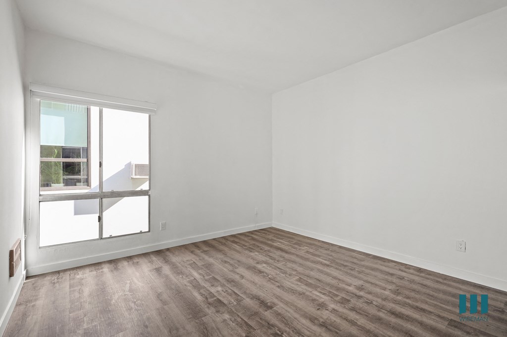 A room with a large window and wooden flooring.