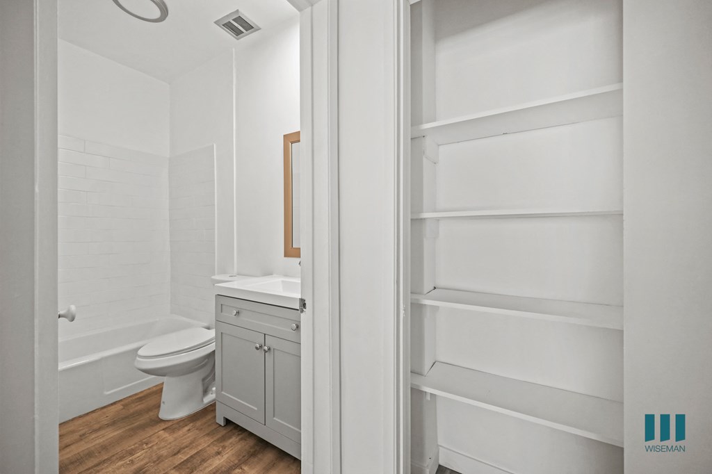 A white bathroom with a toilet and a cabinet.