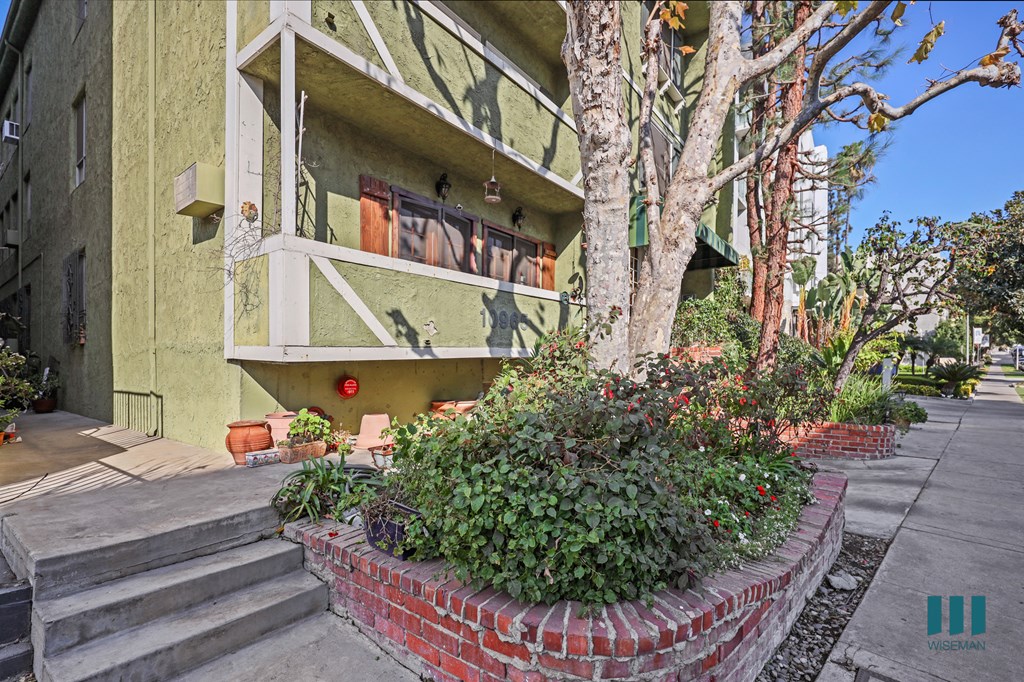 A green building with a red brick planter in front.