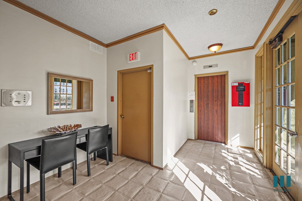 A conference room with a table and chairs and an exit sign on the wall.