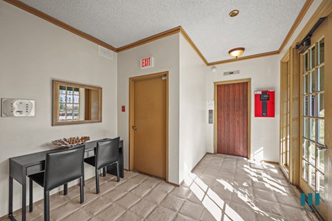 A conference room with a table and chairs and an exit sign on the wall.