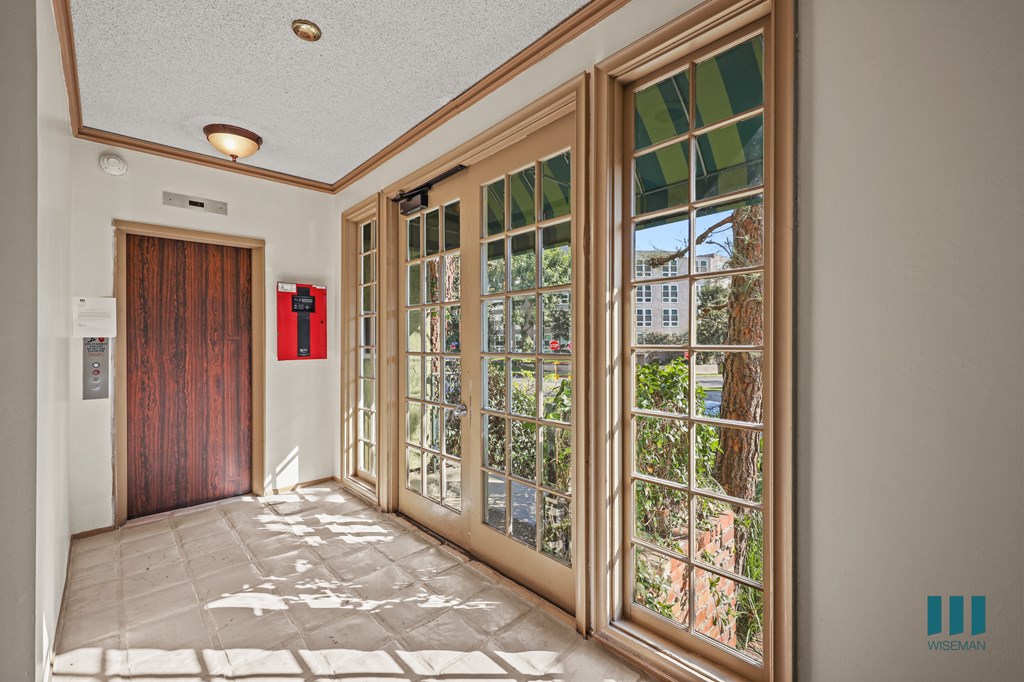 A hallway with a red door and a glass door with a view of trees outside.