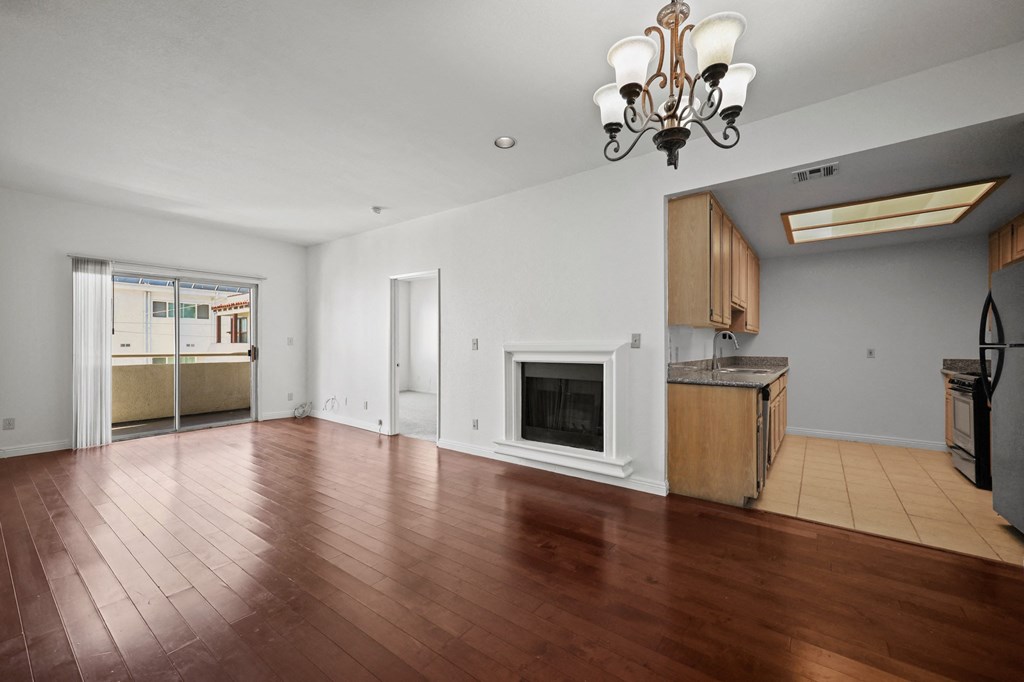 an empty living room with a fireplace and a kitchen