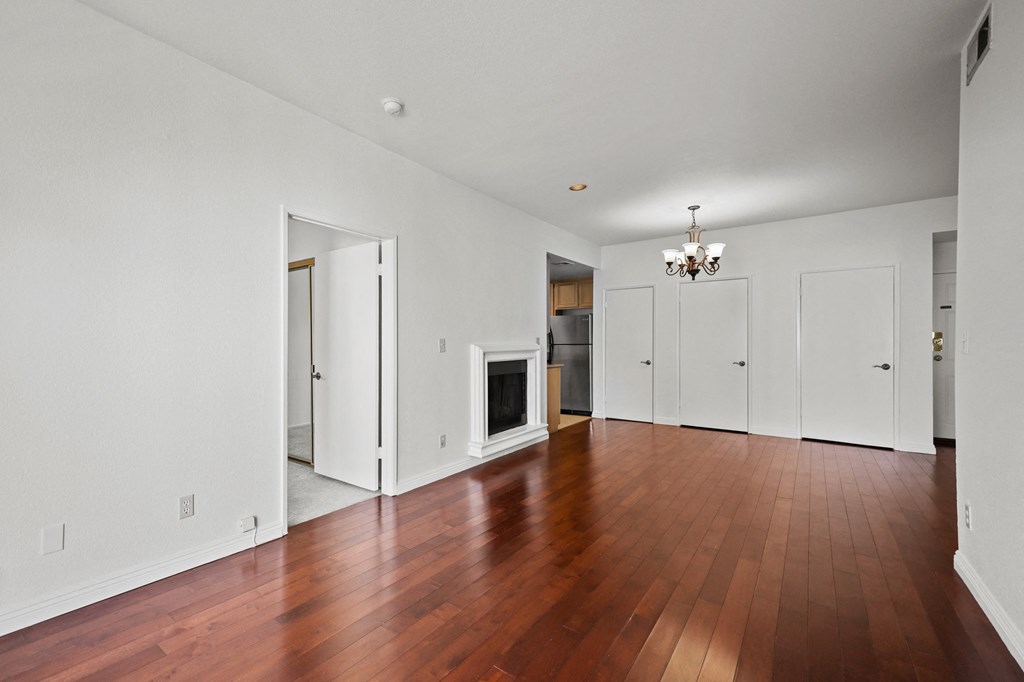 an empty living room with wood floors and a fireplace