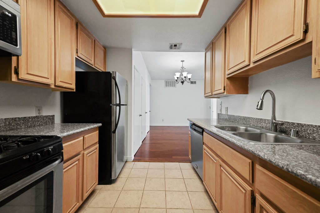 a kitchen with wooden cabinets and a sink and a black refrigerator