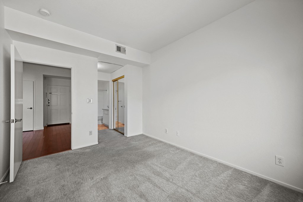 the living room of an apartment with white walls and carpet