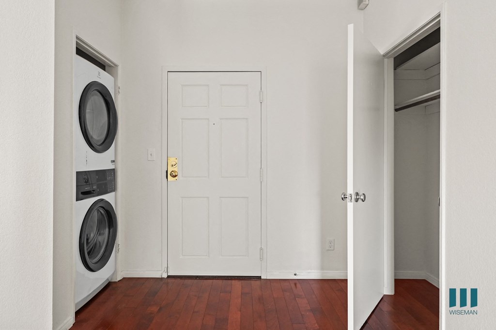A white door with a gold handle is in a room with a washer and dryer to the left.