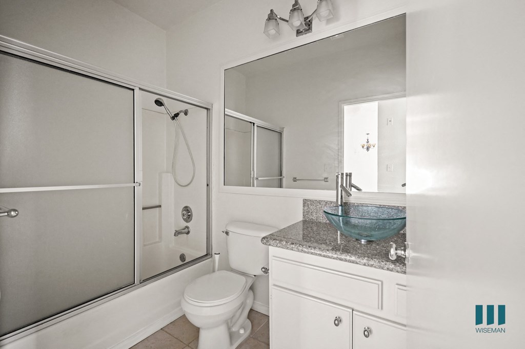 A white bathroom with a toilet, sink, and shower.