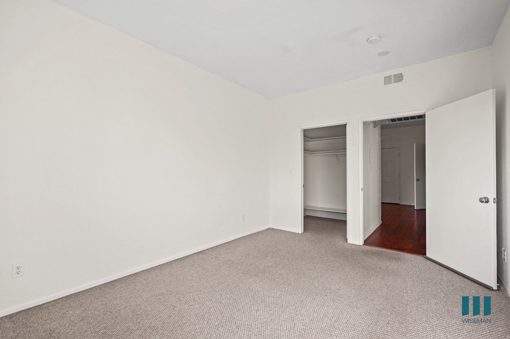 A large empty room with a carpeted floor and white walls.