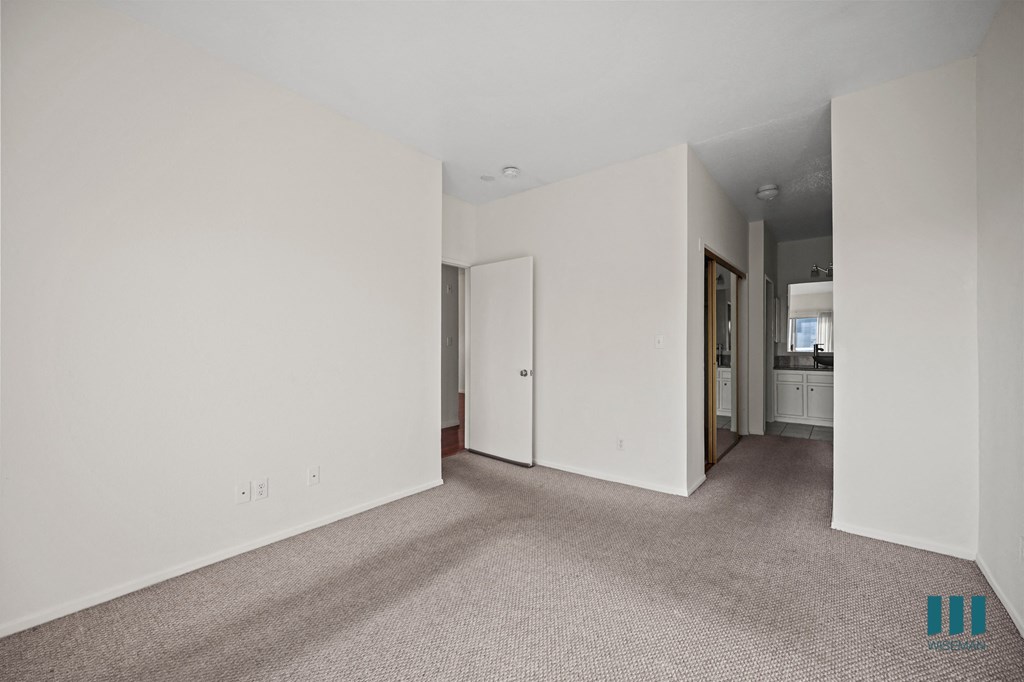 A large empty room with carpeted floor and white walls.