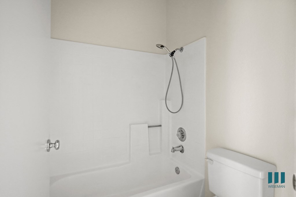 A white bathroom with a tub and toilet.