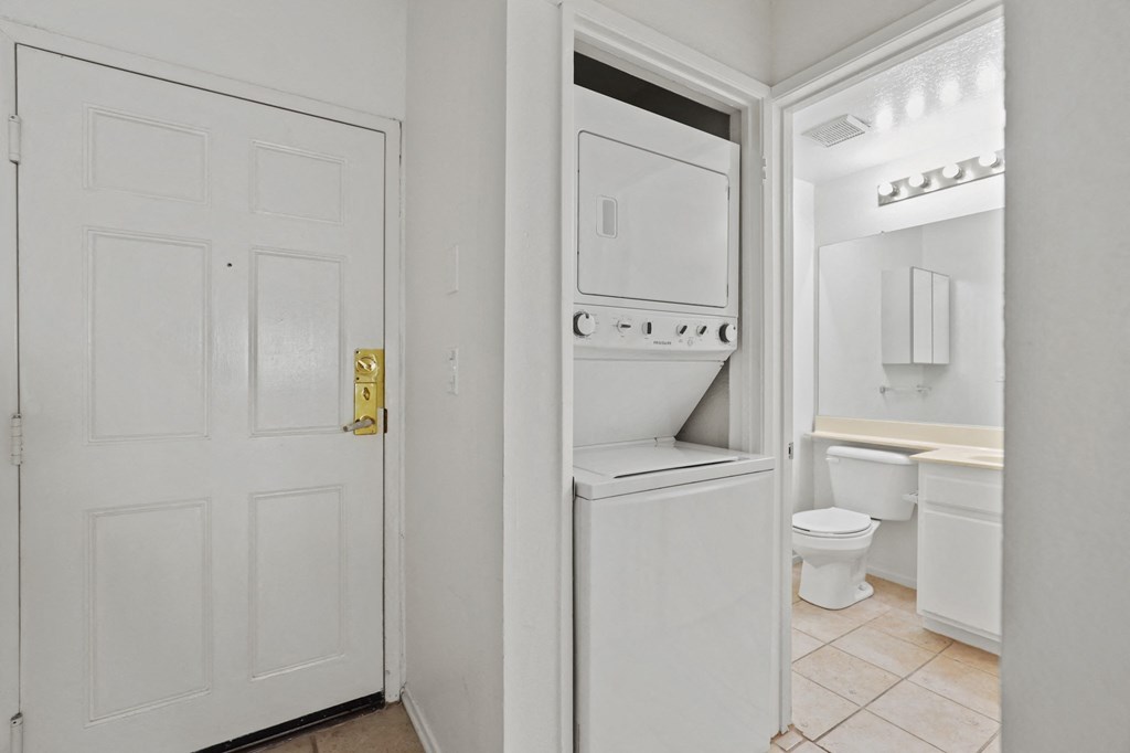 a laundry room with a washer and dryer and a door to a bathroom
