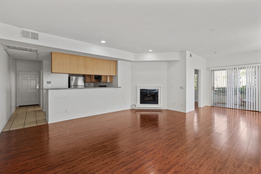 an empty living room with wood flooring and a fireplace