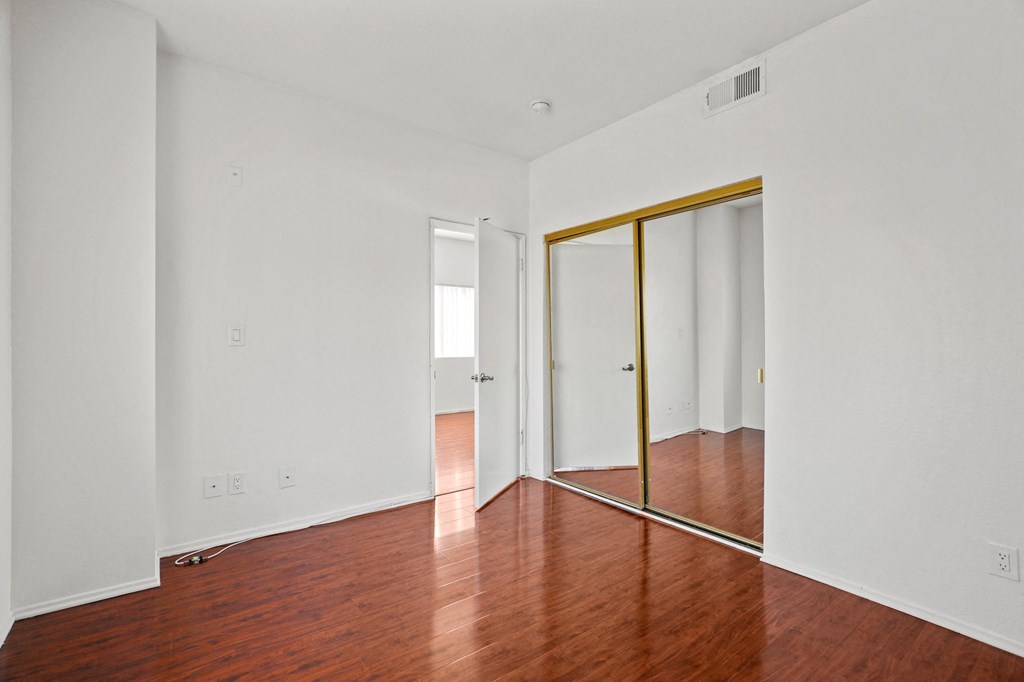 a living room with wood floors and white walls and mirrors