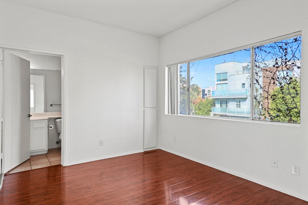 an empty living room with a large window and wooden floors