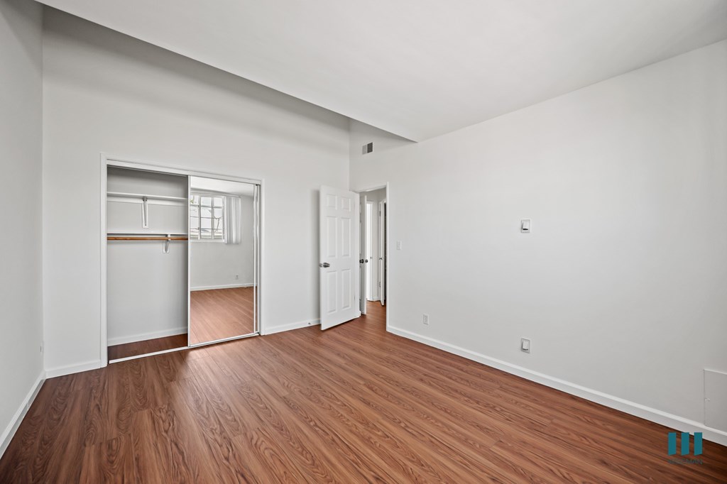 Bedroom with a Mirrored Closet and Hardwood Flooring