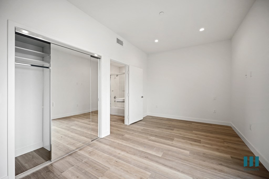 a living room with white walls and wood floors and a mirrored closet