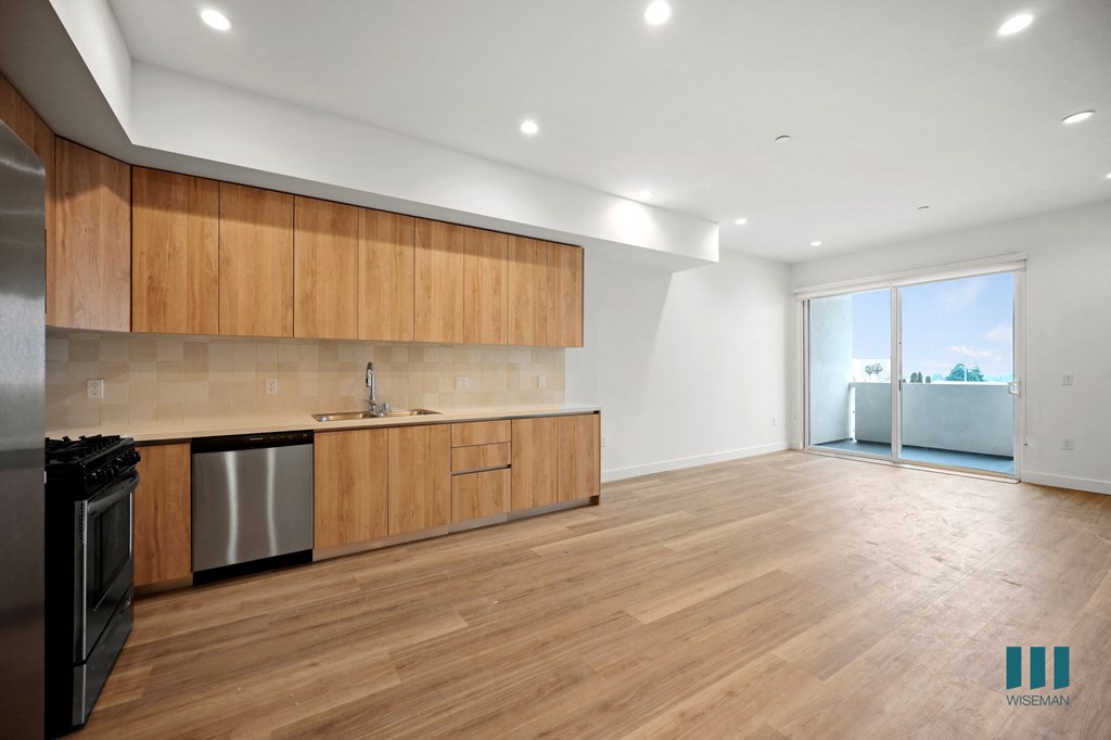 a kitchen and living room with wood floors and wooden cabinets