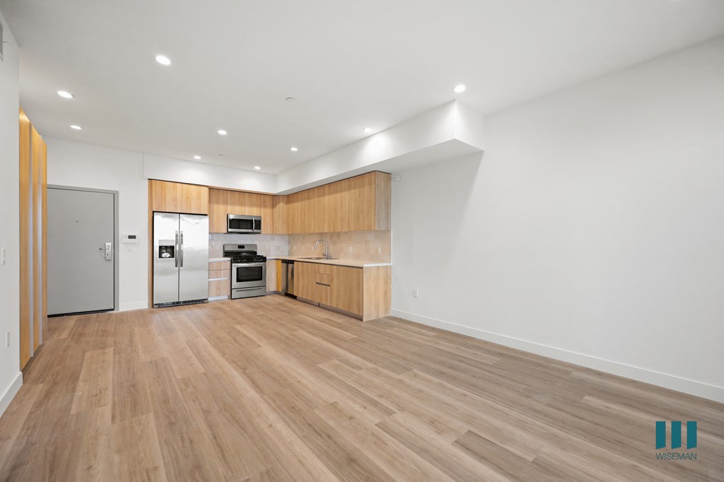 a living room and kitchen with wood floors and white walls