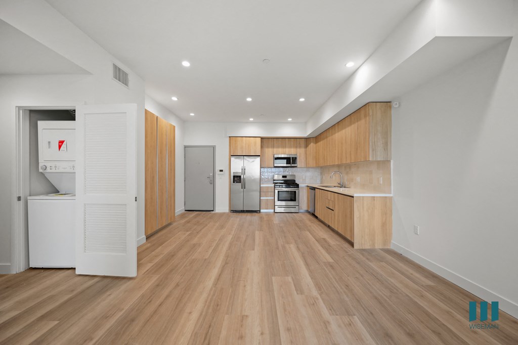 a kitchen with wooden floors and white walls and wooden cabinets