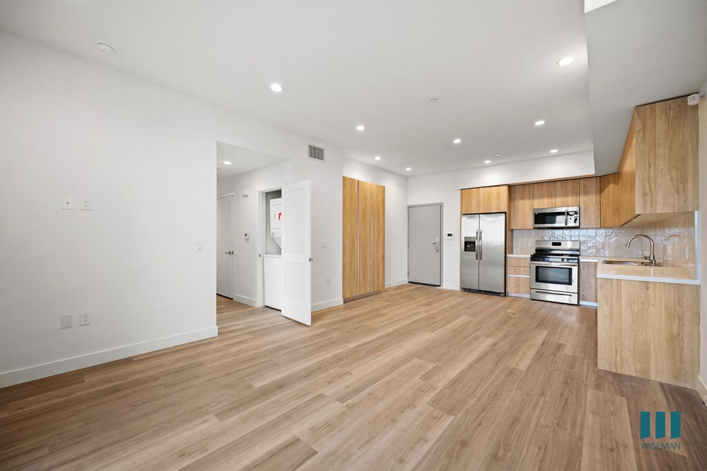 a renovated living room and kitchen with wood floors and white walls