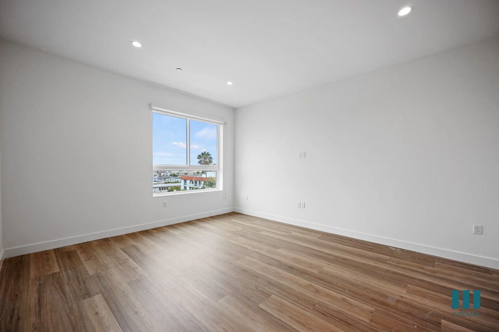 a living room with white walls and wooden floors and a window