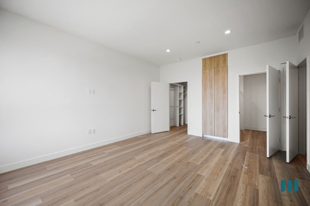 a view of a room with white walls and brown flooring