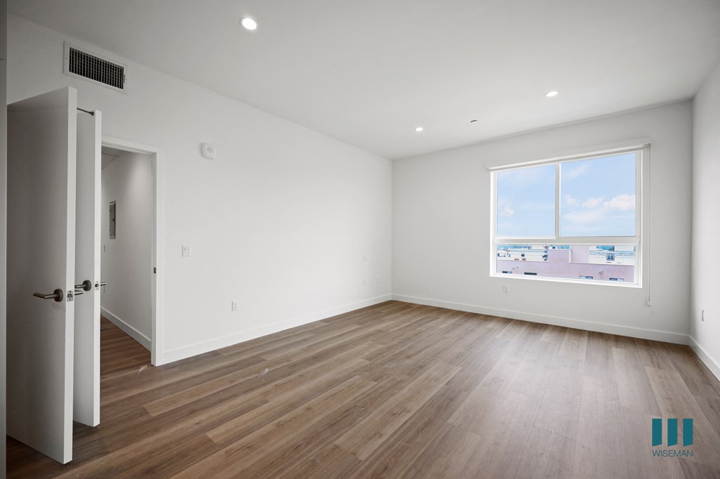 a living room with white walls and wooden floors and a window