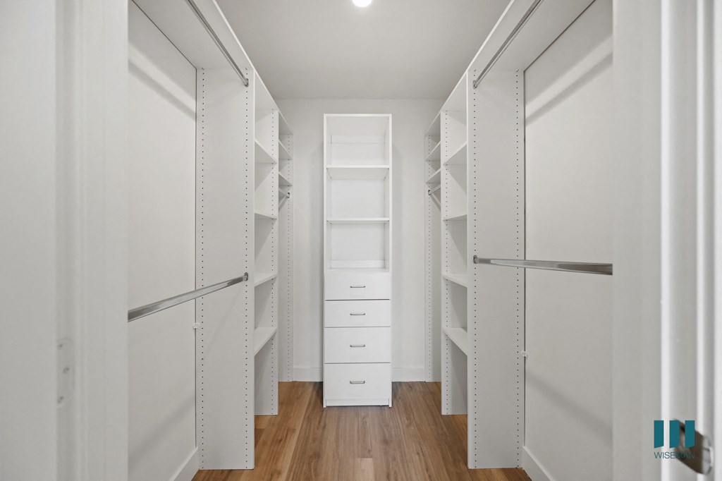 a walk in closet with white walls and white shelves and drawers