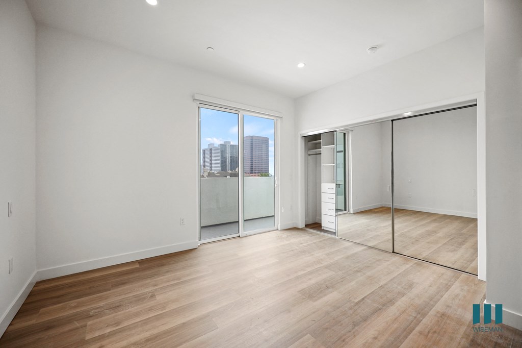 a living room with a hardwood floor and white walls and sliding glass doors