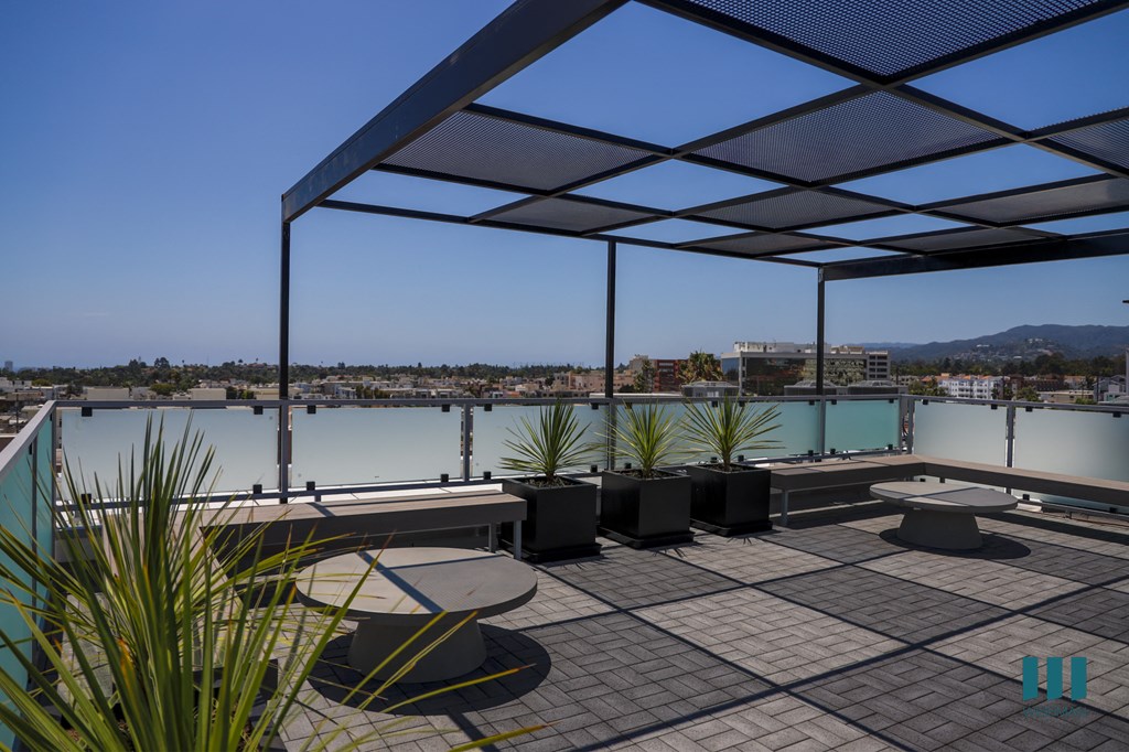 a roof terrace with tables and chairs overlooking a body of water