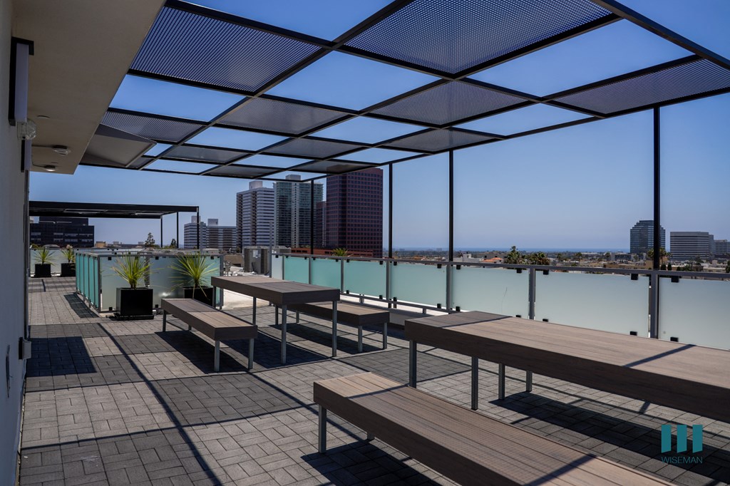 a deck with benches and tables overlooking a body of water and buildings