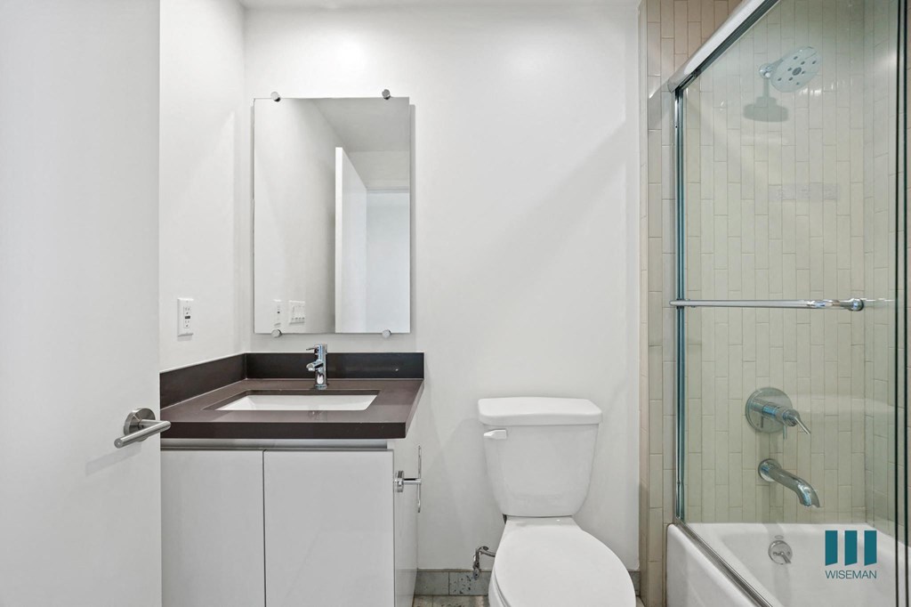 Bathroom with Full-Size Bathtub with Glass Door and Vanity Cabinet Storage