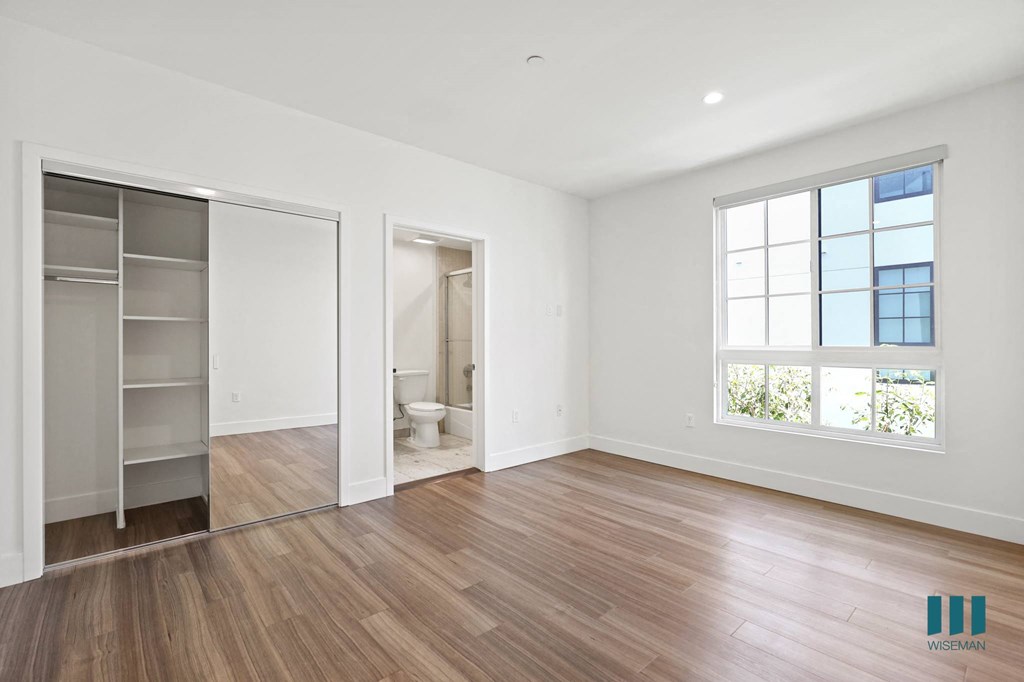 Bedroom with Bathroom, Large Closet with Built-In Shelving, Windows, and Vinyl Flooring
