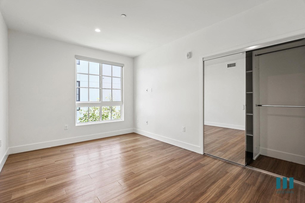 Bedroom with Mirrored Closet, Vinyl Flooring, and Large Windows