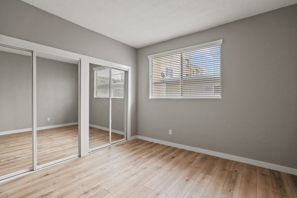 Bedroom with Double Mirrored Closets, Vinyl Flooring, and Window