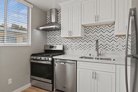 a kitchen with white cabinets and stainless steel appliances and a window