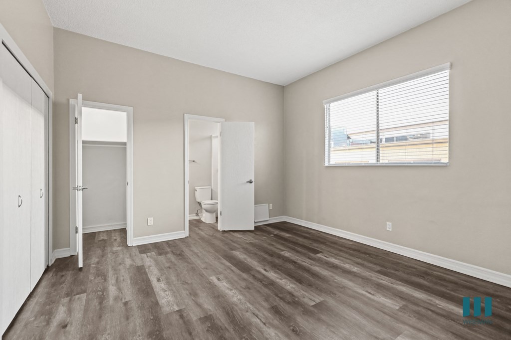Bedroom with Bathroom, Large Windows, Closet, and Vinyl Flooring