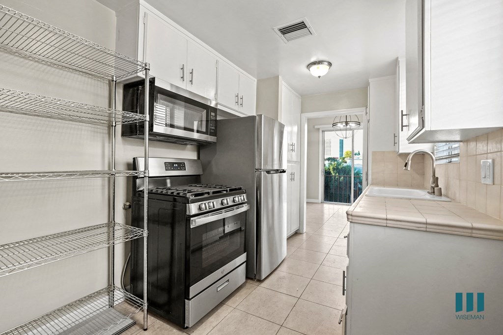 Kitchen with a Stainless-Steel Stove, Refrigerator, Microwave Oven, and Shelving